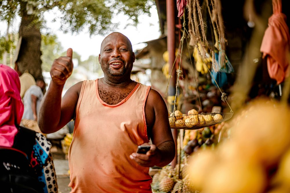 African shop owner using SalesTrack Africa on his phone